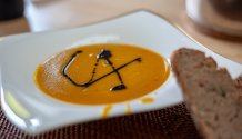 Rezept Foto von der Curry Kürbiscreme Suppe mit einer Scheibe Holzofenbrot vom Biobäcker Kellermann aus Amberg. Garniert mit Kürbiskernöl aus der Steiermark.