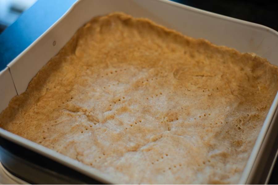 Rezept Foto Lauchzwiebelkuchen backen und genießen. In einer Springform ist der Mürbeteig für den Lauchzwiebelkuchen ausgelegt und mit einer Gabel eingestochen worden.
