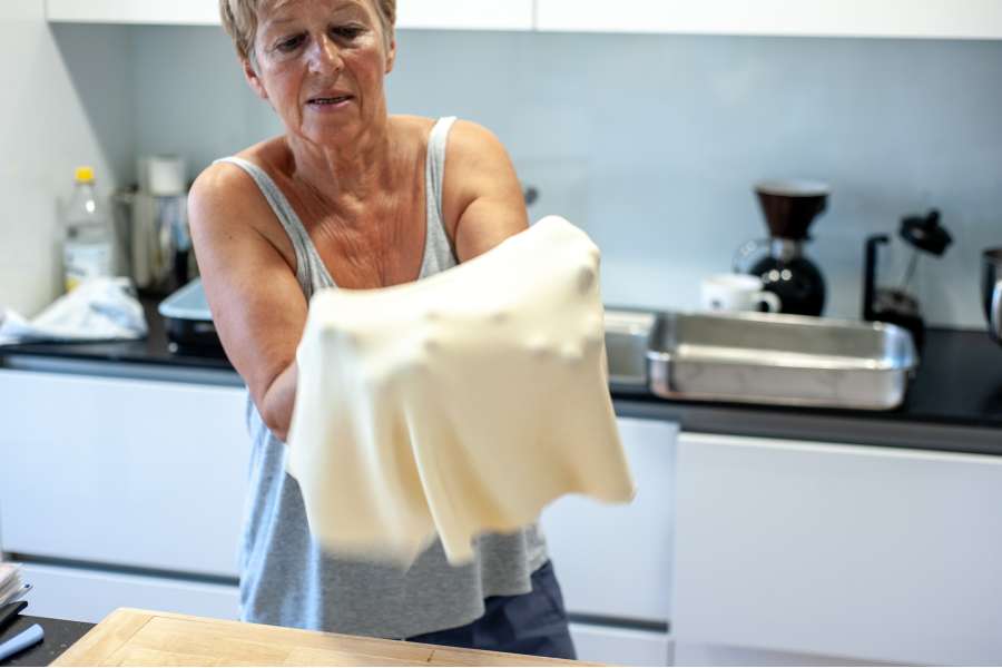 Rezept Foto Oberpfälzer Milchrahm Apfelstrudel. Mama Siglinde nimmt den ausgerollten Teig auf die Hände und zeigt ihn direkt in die Kamera.