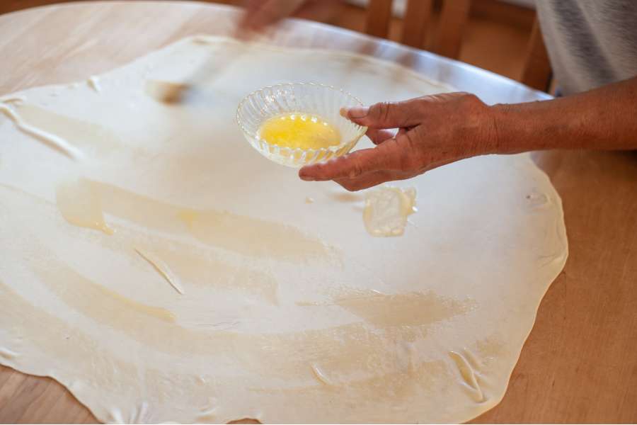 Rezept Foto Oberpfälzer Milchrahm Apfelstrudel. Der Teig wird mit Ei und Butter bestrichen.