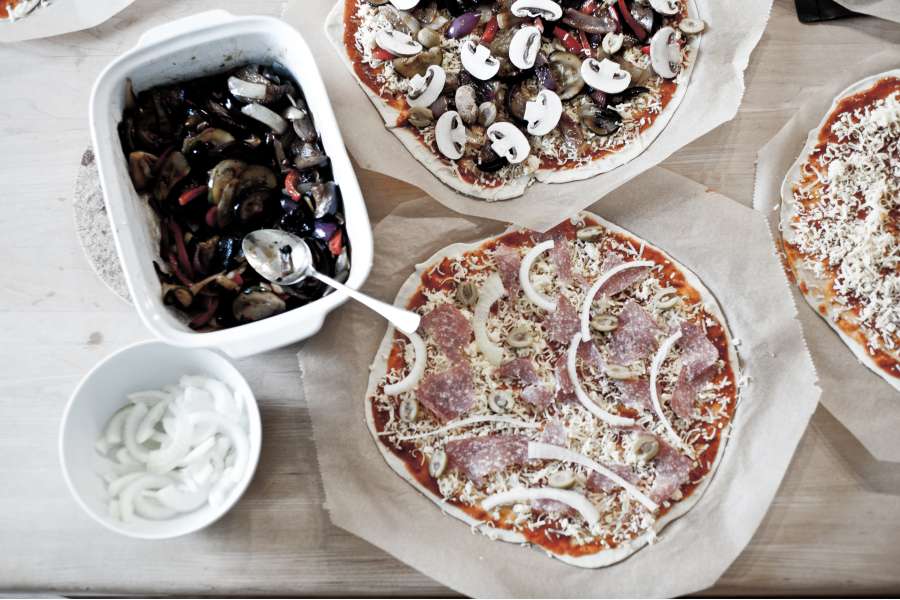 Rezept Foto Grillpizza und Ofenpizza Italien. Vogelperspektive über die belegten Pizzas und Zutaten.
